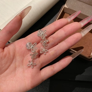 Detailansicht von Vintage-Ohrclips mit hohlen Blumenquasten, in der Hand gehalten.