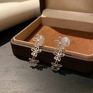 Nahaufnahme von silbernen hohlen Blumen-Ohrclips an einer Schmuckschatulle.