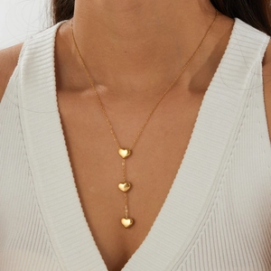 Close-up detail of a gold-plated stainless steel Y-necklace with three heart pendants