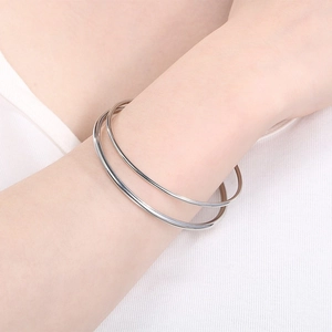 Minimalist silver stainless steel round wire bangle bracelet set on female wrist.