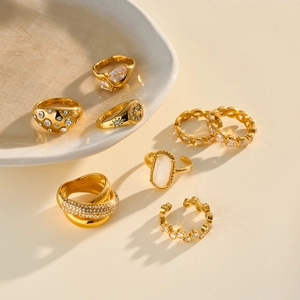 Detailed view of assorted gold-plated stainless steel rings with zircon and cat eye stones.