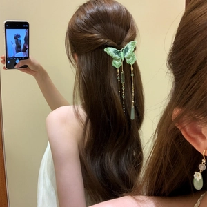Gros plan d'une pince à cheveux papillon vert tricoté avec perles et pompons élégants.