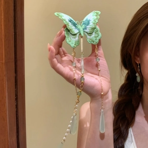 Detailed view of an elegant green knitted butterfly hair clip with pearl tassels.