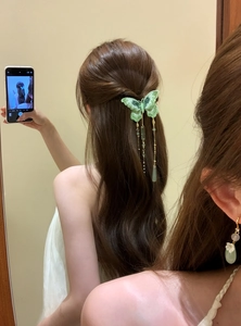 Close-up detail of a green knitted butterfly hair clip with elegant pearls and tassels on hair