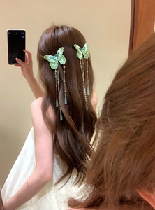 Detailed view of green knitted butterfly hair clip with long elegant tassels and beads