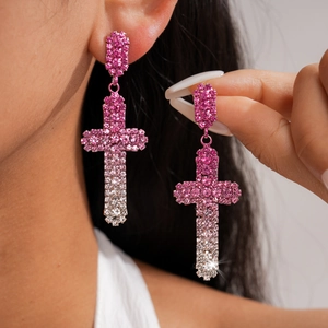 Gros plan de boucles d'oreilles croix en strass rose avec effet dégradé