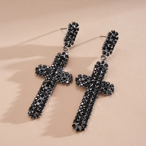 Détail de boucles d'oreilles en forme de croix serties de strass noirs élégants