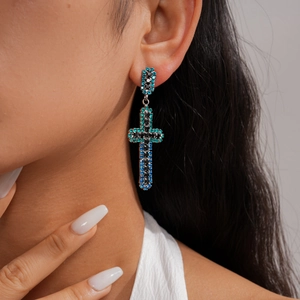 Vue rapprochée d'une boucle d'oreille en croix avec strass bleus et noirs étincelants.