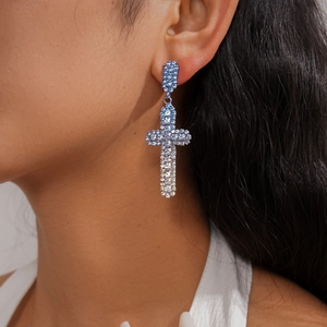 Gros plan de boucles d'oreilles croix élégantes avec strass bleus et clairs dégradés