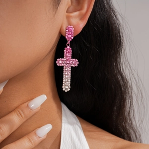 Gros plan détaillé de boucles d'oreilles croix en strass rose portées par un mannequin