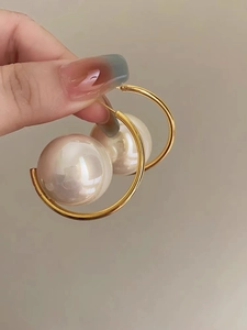 Close-up of elegant gold-plated oval pearl hoop earrings in vintage style