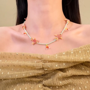 Dettaglio di collana colorata in perline di vetro con ciondoli a forma di pesce a mano