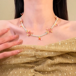 Primo piano di una collana di perline fatta a mano con ciondoli a pesce su una modella