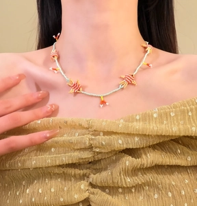 Dettaglio di una collana in perline di vetro colorate con ciondoli a forma di pesce