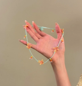 Dettaglio macro di una collana di perline colorate con simpatici ciondoli a forma di pesce