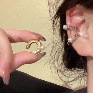 Close-up detail view of gold and silver pearl ear cuffs worn on ear and held by hand