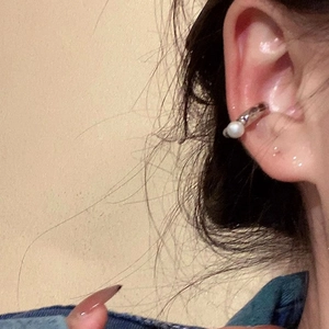 Close-up view of a minimalist silver pearl ear cuff worn on a non-pierced ear detail