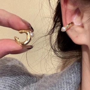 Minimalist gold-plated C-shaped ear cuff with white pearl detail shown worn on ear