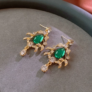Detailed view of vintage emerald green teardrop earrings with gold leaf-shaped crystal settings