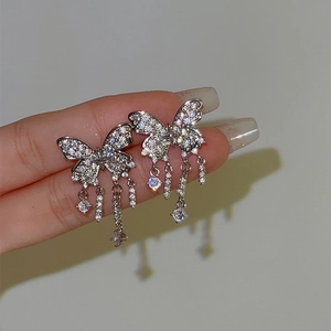 Macro detail of a sparkling butterfly tassel ear cuff with dangling clear stones