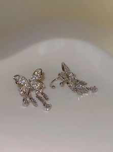 Macro view of elegant silver butterfly tassel ear cuffs adorned with shimmering crystals