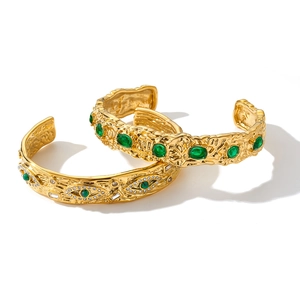 Dettaglio di bracciali rigidi in oro con pietre verdi e strass scintillanti