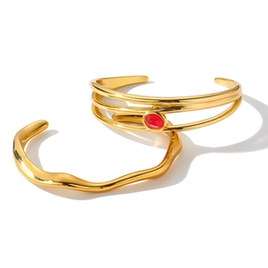 Primo piano di due bracciali rigidi in acciaio inox dorato con pietra rossa