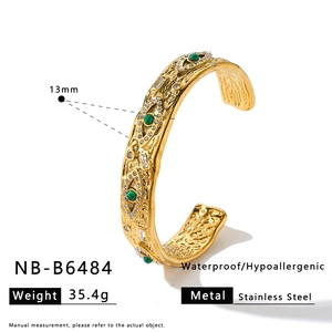 Dettaglio ravvicinato di un bracciale rigido in acciaio inossidabile dorato con pietre
