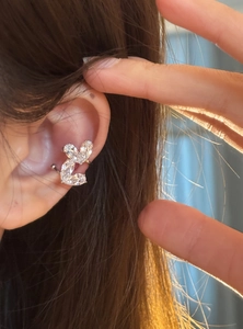 Primo piano dettagliato di un ear cuff con doppio cuore in zircone su un orecchio umano.