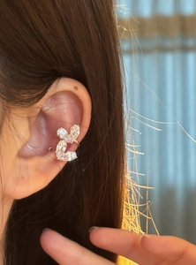 Dettaglio ravvicinato di un ear cuff a forma di cuore con zirconi indossato sull'orecchio.