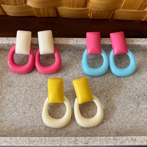 Primer plano de aretes geométricos de resina retro coloridos en tonos rosa, azul y amarillo