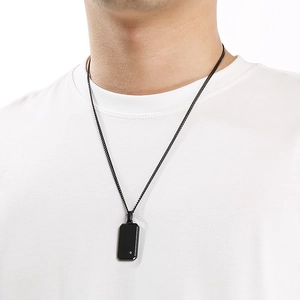Detalle de collar con colgante cuadrado negro minimalista con diamante en camiseta blanca de hombre