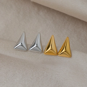 Gros plan de boucles d'oreilles triangles géométriques en finitions or et argent poli
