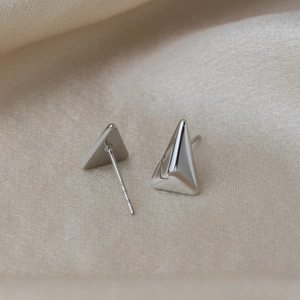 Détail macro de boucles d'oreilles triangles géométriques argentées au fini poli miroir