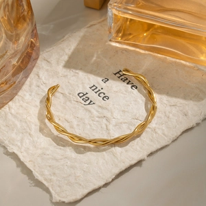 Detailed close-up of a minimalist twisted rope cuff bracelet with 18K gold plating