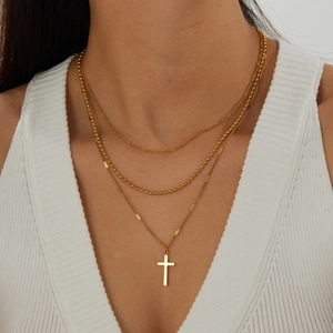 Detail view of gold layered necklace with bead chain and polished cross pendant