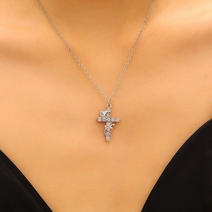 Close-up of a silver crown cross necklace with rose relief and sparkling zircons