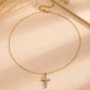 Detailed shot of golden cross necklace with crystal zircon and a small 3D rose detail