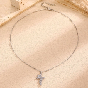 Close-up of a silver cross pendant with sparkling zircons and delicate rose flower details