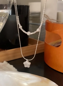 Detail view of an elegant double-layered necklace featuring pearls and a star charm