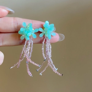 Vue détaillée de boucles d'oreilles fleuries vert menthe avec pompons de perles roses