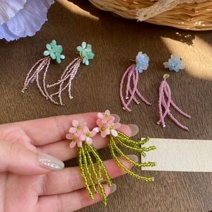 Gros plan de boucles d'oreilles fleurs en perles colorées avec détails artisanaux.