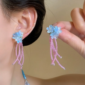 Détail de boucles d'oreilles fleurs bleues avec pampilles de perles roses pour les vacances