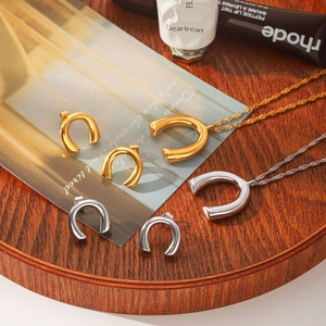 Detail view of minimalist gold and silver U-shaped pendant necklace and matching stud earrings