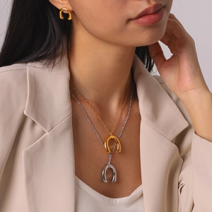 Close-up detail of a model wearing stylish gold and silver U-shaped pendant necklaces.