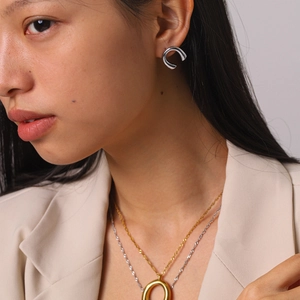 Close-up of a model wearing minimalist silver U-shaped earrings and a gold necklace