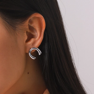Close-up detail of a minimalist silver-colored U-shaped earring worn on a female ear