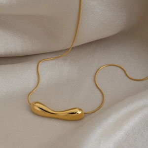 Macro shot of gold plated snake chain with minimalist organic shaped metal pendant