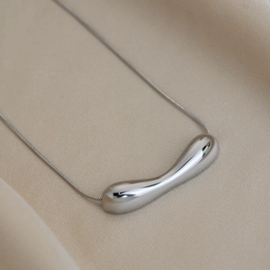 Detailed macro view of a minimalist stainless steel pendant on a sleek snake chain necklace