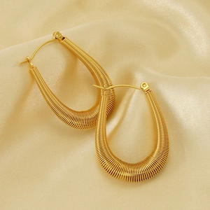 Primer plano de aretes de aro dorados con diseño de resorte y textura elegante